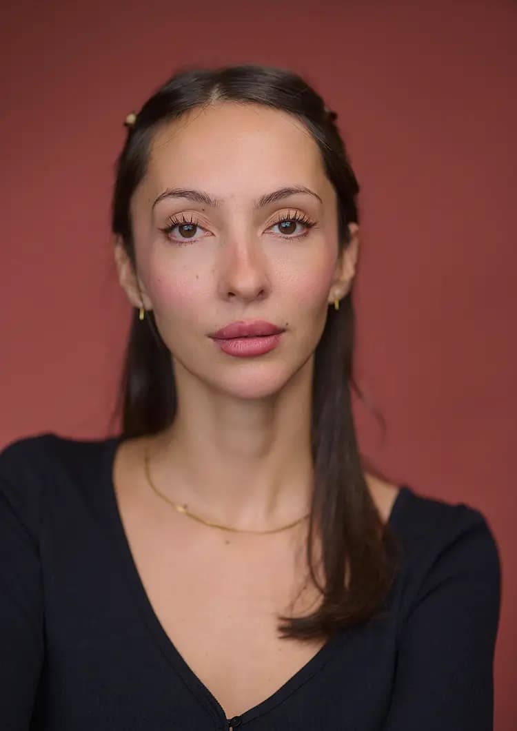 Seated actor headshot of Rosie Lou photographed on a terracotta canvas backdrop