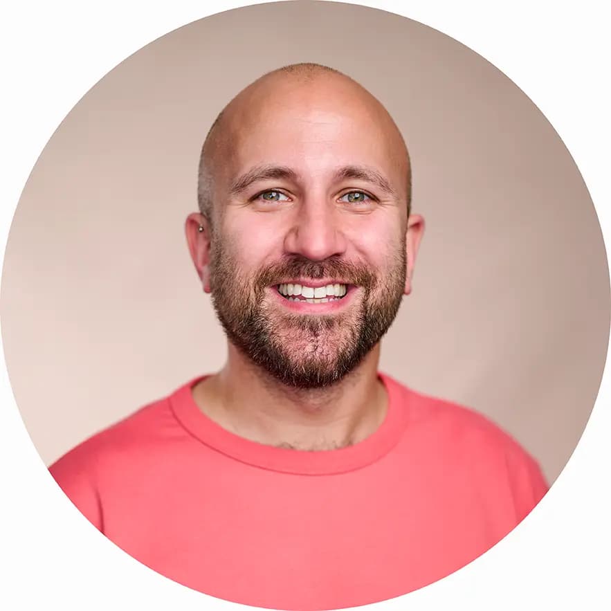 Modern business headshot in London of a smiling professional photographed on a pink canvas backdrop